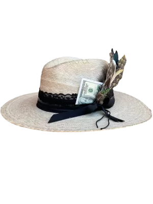 Sombrero estilo panama de palma con aplicaciones; carta de dólar, plumas, tiras de encaje y vinipiel.